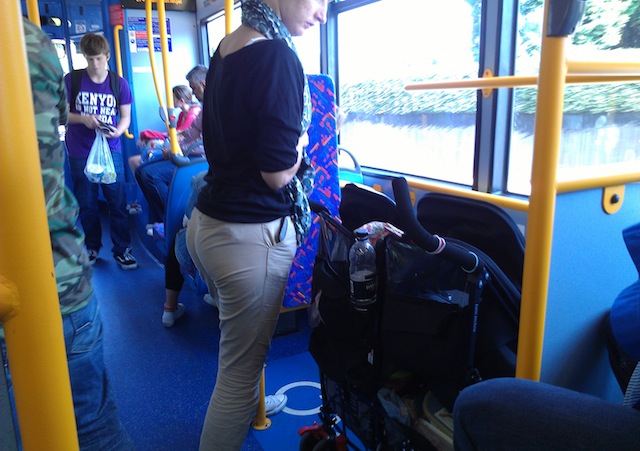 Mãe com carrinho de bebê para gêmeos num ônibus de Londres